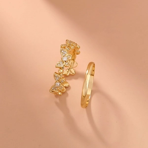 Detailed view of gold butterfly ring set with pavé cubic zirconia on pink background