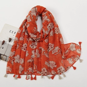 Detail of vibrant orange floral print scarf featuring delicate tassels and cotton-linen texture