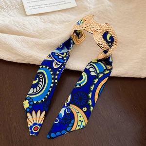 Detail of bohemian gold buckle with royal blue floral silk ribbon on retro background
