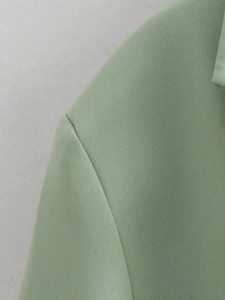Detailed view of sage green blazer shoulder seams and fine twill fabric texture