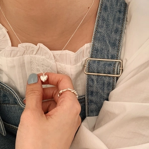 Elegant silver heart pendant necklace and twisted ring set on model in denim