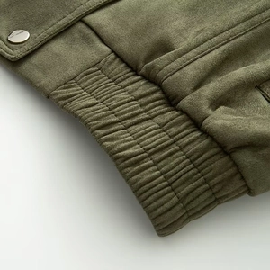 Dettaglio della giacca verde oliva con texture scamosciata opaca e polsino a coste