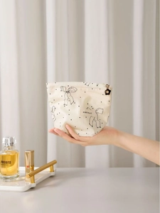 Chic cream canvas makeup bag with black bow pattern and floral zipper pull