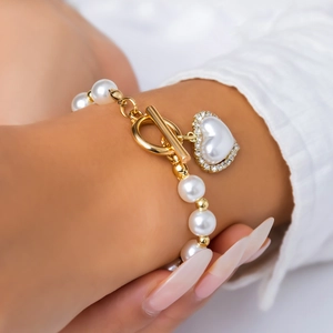 Detail of pearl bracelet with golden toggle clasp and sparkling diamond heart charm
