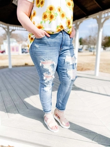 Détail du jean skinny déchiré bleu clair avec t-shirt imprimé tournesol et sandales roses