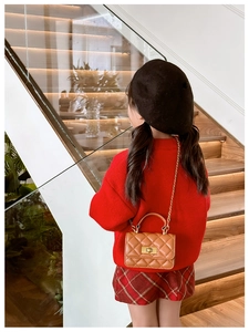 Girl wearing a brown quilted crossbody bag with gold chain strap on a wooden staircase