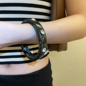 Detail view of black marble acrylic bangle with crystal rhinestones on a female wrist