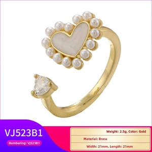 Detail of gold heart ring with white enamel, pearls and zircon on brass band