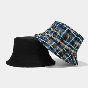 Detail view of double-sided bucket hats in solid black and colorful plaid canvas fabric