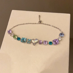 Macro detail of adjustable silver bracelet with colorful mixed-cut gemstones and heart crystal