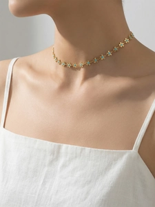 Détail du ras de cou plaqué or 18k avec fleurs en émail bleu sur le cou du mannequin