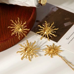 Flat lay view of 18k gold sun pendant necklace and earrings on a wooden tray set