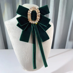 Elegant dark green velvet bow brooch with crystal oval centerpiece on beige mannequin