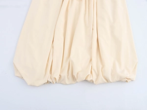 Detail of elegant beige bubble hem midi dress showing soft pleated chiffon fabric texture