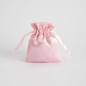 Pink satin drawstring gift bag for jewelry with smooth silk texture on white background