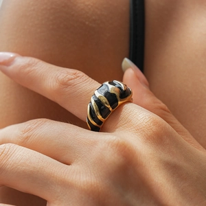 Macro shot of a spiral textured black enamel ring with gold metal finish on finger