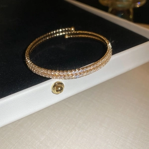 Macro detail of gold double-row rhinestone spiral bangle in luxury jewelry gift box
