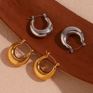 U-shaped hollow earrings in gold and silver finish displayed on a rustic wood surface
