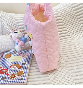 Detail of pink quilted tote bag with heart patterns and cute cartoon puppy embroidery