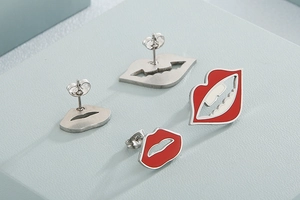 Macro shot of lip-shaped stud earrings in red enamel and silver hollow-out designs
