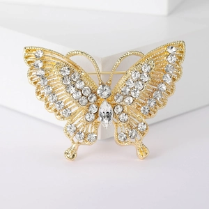 Macro shot of gold butterfly brooch with intricate filigree wings and clear crystals