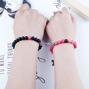 Close-up of magnetic heart clasp connecting black and pink natural stone bead bracelets