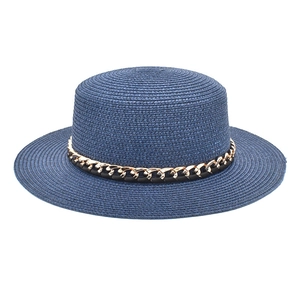 Détail d'un canotier en paille bleu marine avec chaîne dorée et ruban en cuir noir