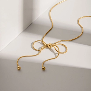 Detail of golden snake chain necklace with a unique pull-through butterfly knot design