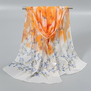 Détail du foulard en mousseline avec dégradé orange et motif floral bleu délicat