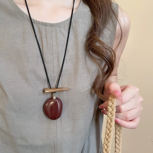 Detail of vintage mushroom pendant necklace with red resin stone and wooden beads on model