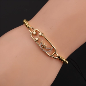 Detailed close-up of a gold-plated moon and star charm bracelet with zircon inlay