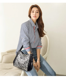 Chic zebra print tote bag with black handles held by a model in a casual setting