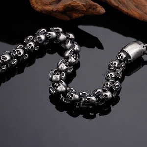 Macro shot of retro silver skull chain bracelet with gothic punk aesthetic on black background