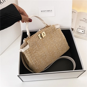 Detail of woven straw handbag with white leather trim and gold twist-lock closure