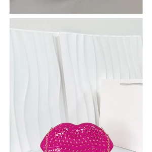 Detail of fuchsia lip-shaped clutch bag with golden studs and metal chain strap