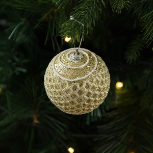 Close-up of golden glitter Christmas ball with woven texture hanging on tree