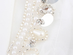 Detail of hand-sewn pearls and rhinestones on mesh fabric of the white dress