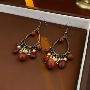 Vintage metal water drop tassel earrings with reddish brown beads on leather tray