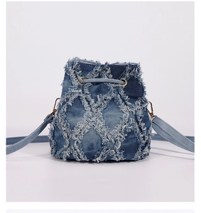 Detail of light blue denim bucket bag with quilted raw edges and gold hardware accents