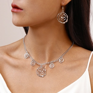 Detailed view of silver minimalist necklace and earrings set featuring spiral flower design