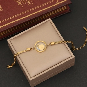 Macro view of gold evil eye pendant with coin charm on a twisted chain necklace