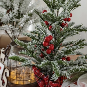 Mini frosted pine needle Christmas tree with red berries and a plaid bow ornament