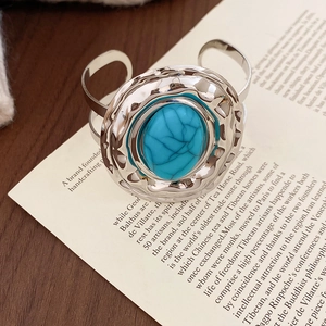 Bracciale vintage martellato color argento con intarsio in turchese su un libro aperto