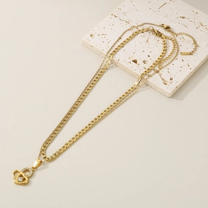 Detail of double-layer gold heart necklace featuring a single zircon on beige stone