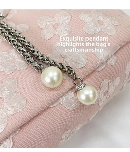 Detail of silver metal chain with large white faux pearls and crystals on a pink lace bag