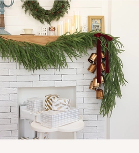 Close-up of festive green cypress garland with bronze bells and a red velvet bow