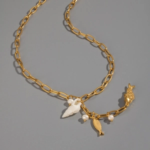 Flat lay of gold chain necklace with conch pendant, koi charms and white pearls