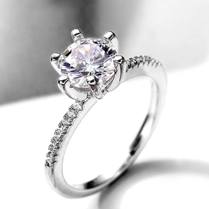 Macro shot of six-prong solitaire ring with pave diamonds on a polished silver band