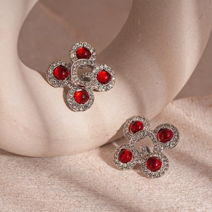 Close-up of vintage resin studs with four red gemstones and crystal letter G details