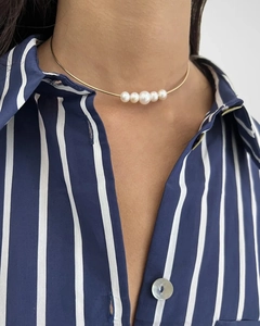 Detail of 18k gold plated choker with five white pearls worn on neck over striped shirt